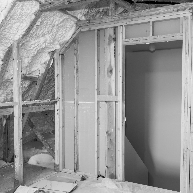 Black and white photo of spray fibre insulation in an attic.