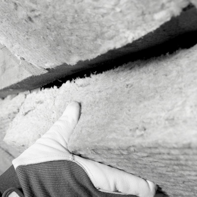 Black and white photo of a gloved hand removing insulation.