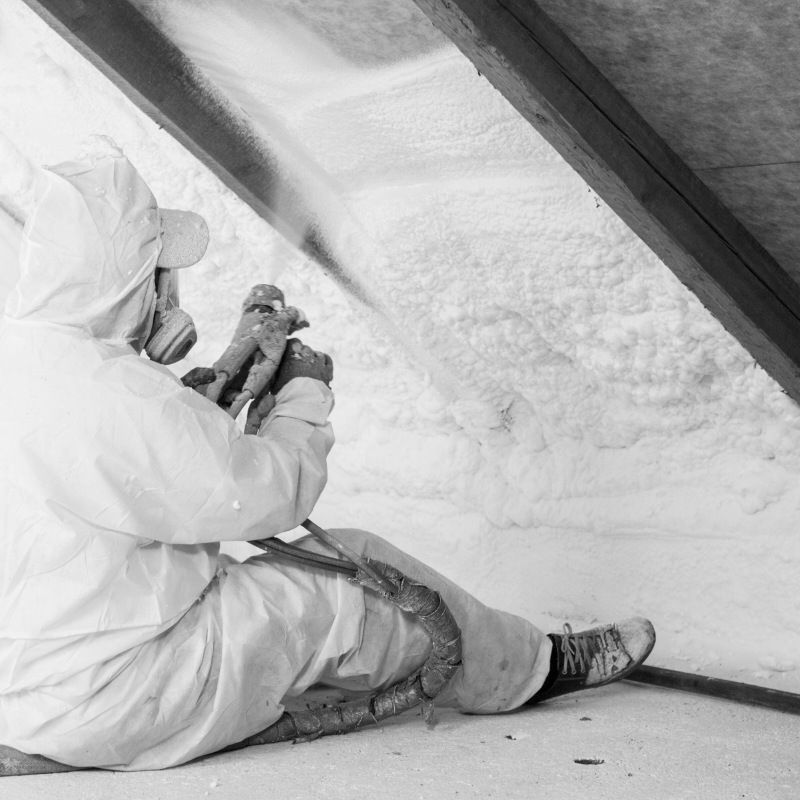 Black and white photo of a person spraying fibre insulation.