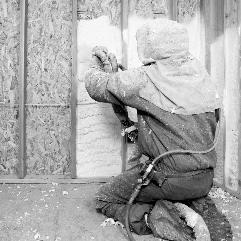 Black and white photo of a person spraying insulation.